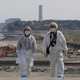 Una pareja camina por las costas cercanas a la devastada central de Fukushima, usando ropa protectora. AP